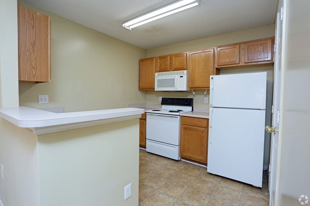 an empty kitchen with white appliances and wooden cabinets