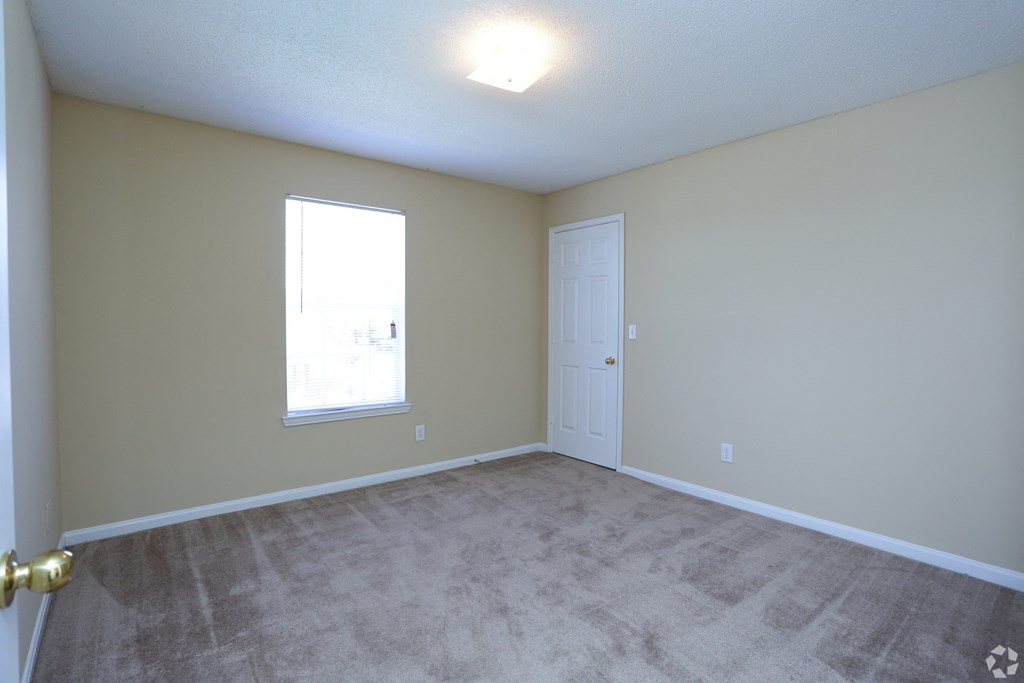 an empty living room with a door and a window