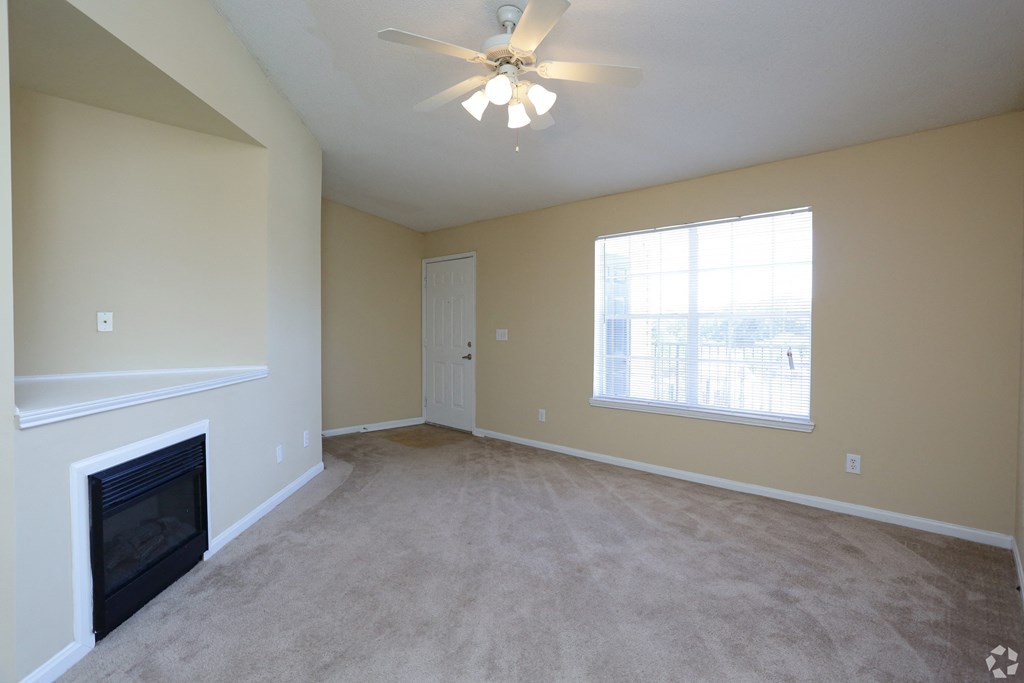 an empty living room with a fireplace and a ceiling fan