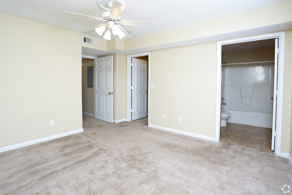 an empty living room with a ceiling fan and a closet