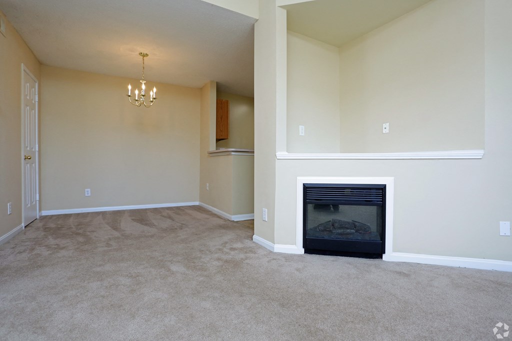 an empty living room with a fireplace and a chandelier