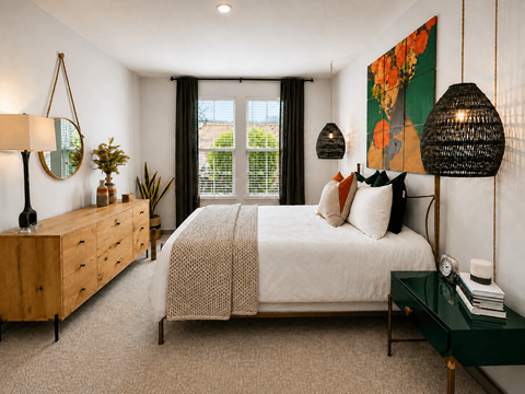 A bedroom with a large bed, a wooden dresser, and a green side table.
