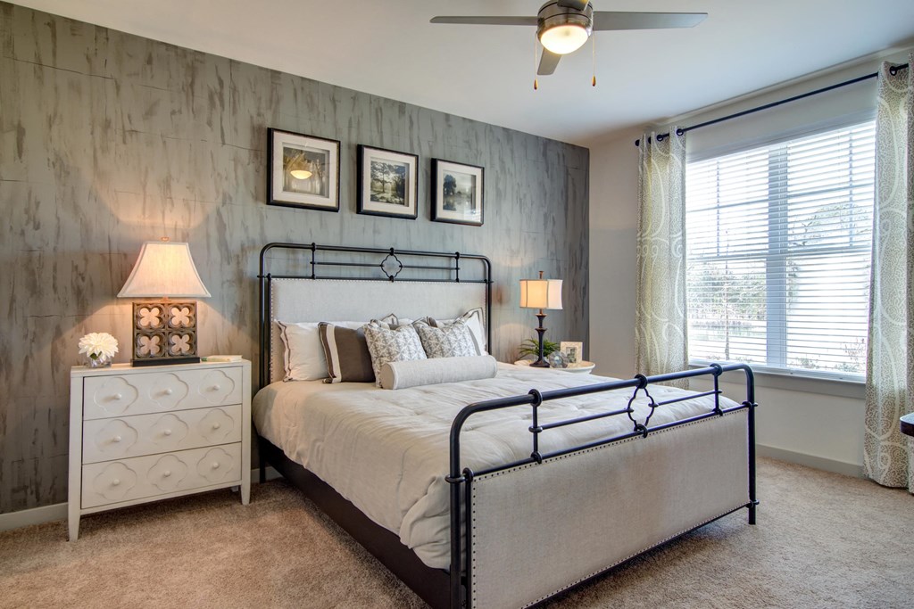 Vestavia Reserve Apartment with Wood Inspired flooring and washer and dryer sets in every home as well as an open layout bedroom with a bed, nightstand, and a ceiling fan.
