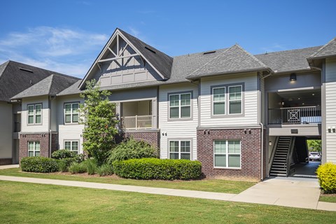 A large, modern house with a grey roof and a large front yard.