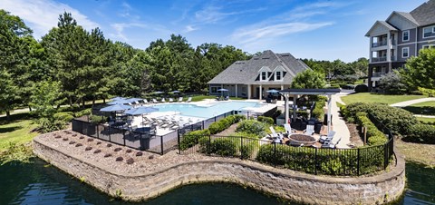 A large house with a pool and a hot tub on a landscaped island.