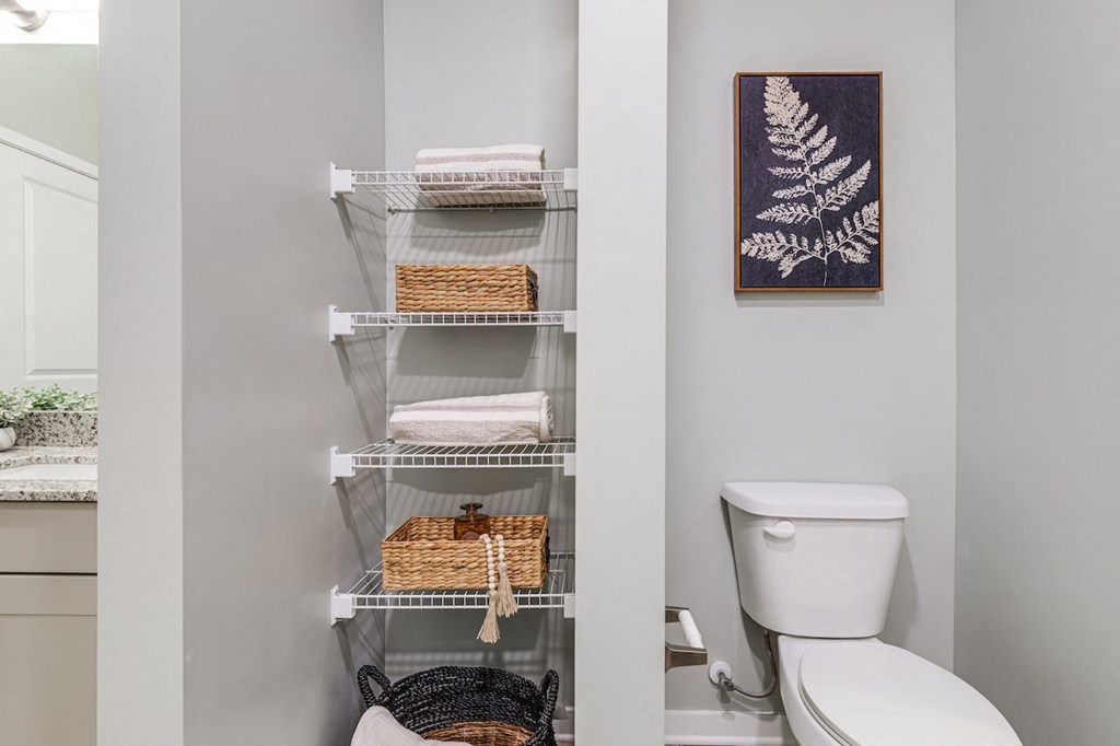 a bathroom with a toilet and a shelf with towels