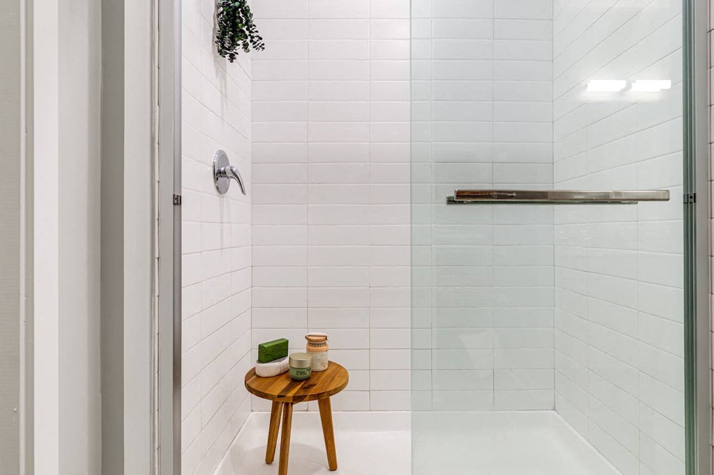 a white bathroom with a shower and a small wooden table