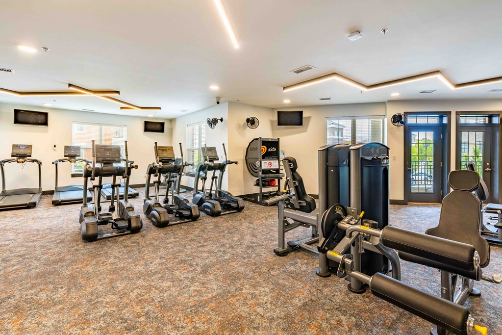 a gym with weights and cardio equipment in a room with windows