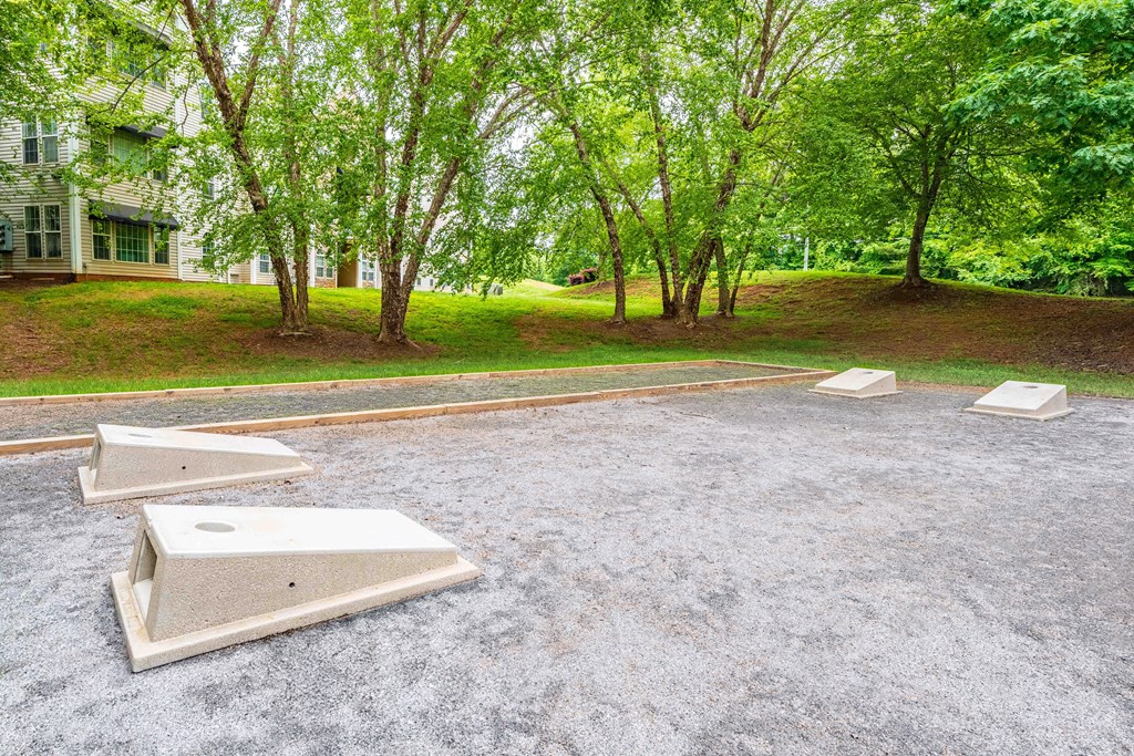 an empty parking lot with trees and a house in the background