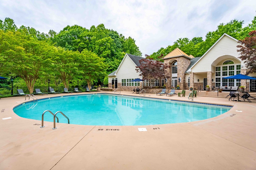 a swimming pool with a house and trees in the background