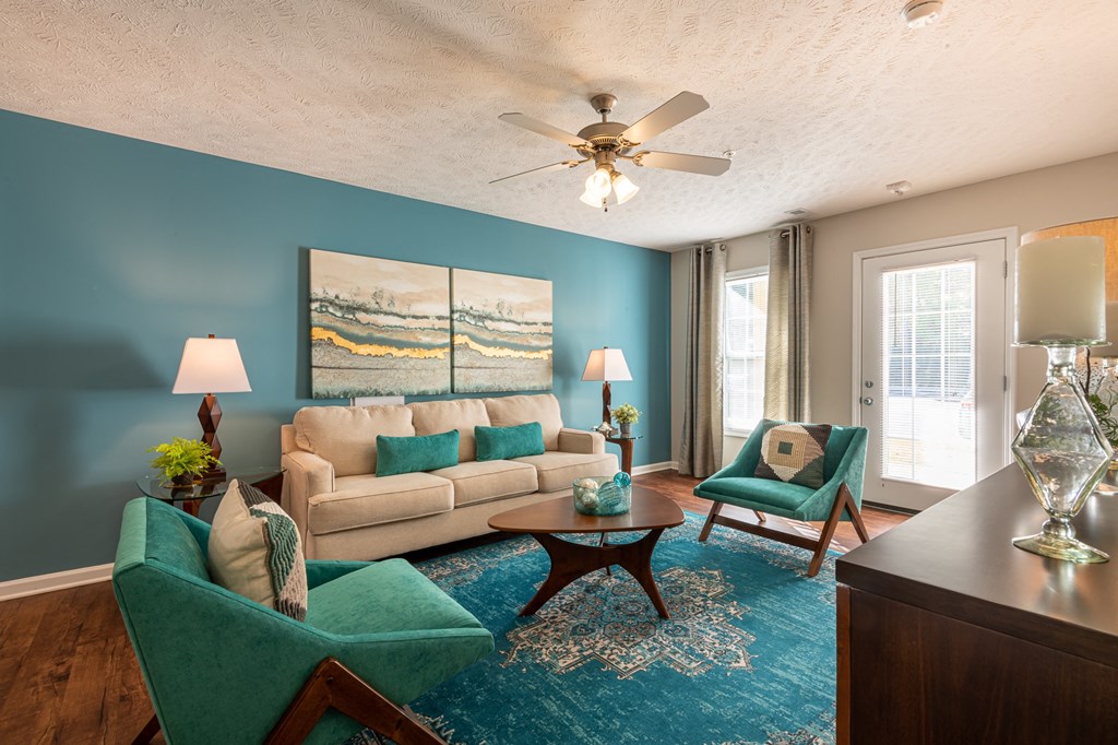a living room with a couch and chairs and a ceiling fan
