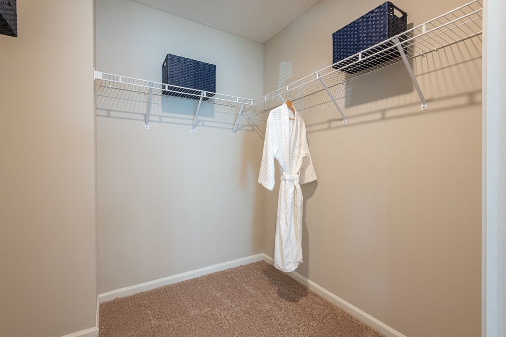 a closet with a white robe and a rack on the wall