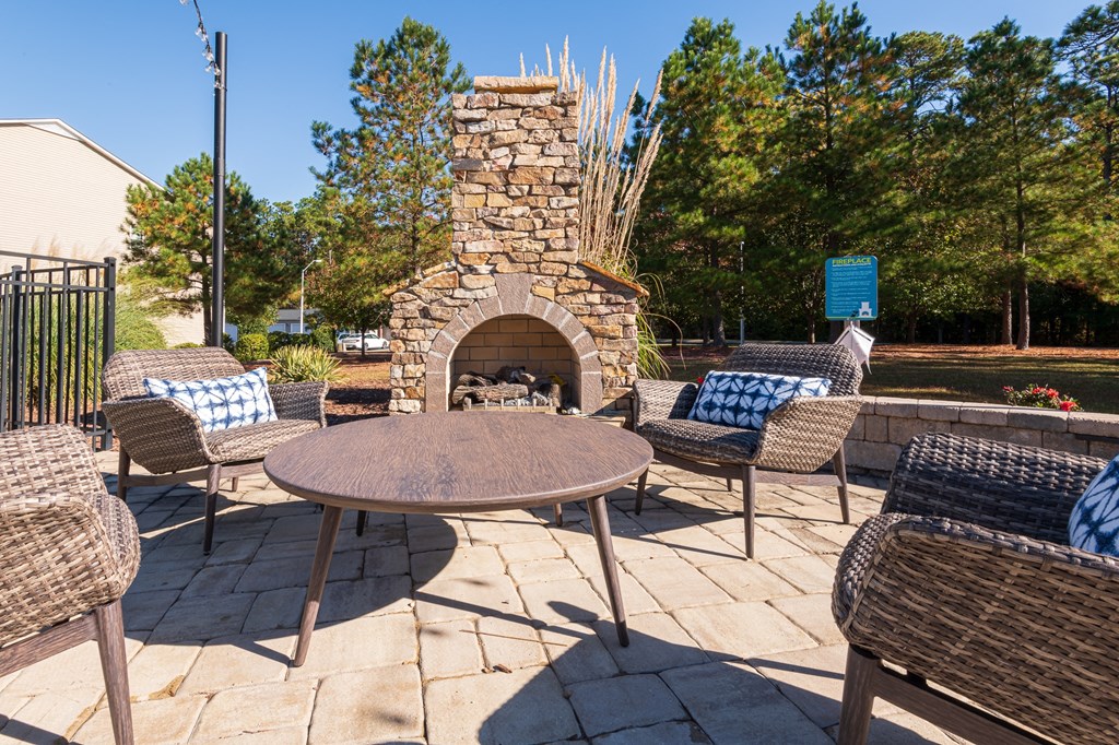 a patio with tables and chairs and a stone fireplace