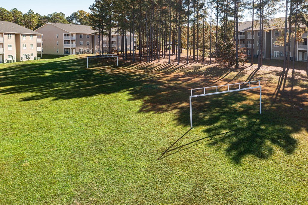 a park with a basketball court and a bench in the grass