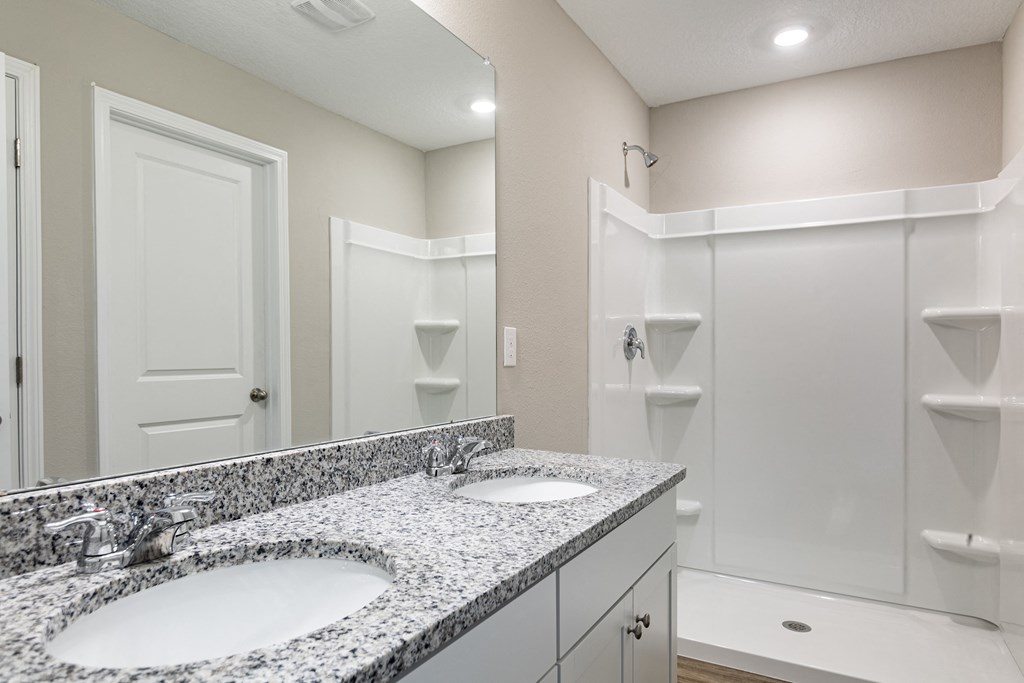 a bathroom with two sinks and a shower and a mirror