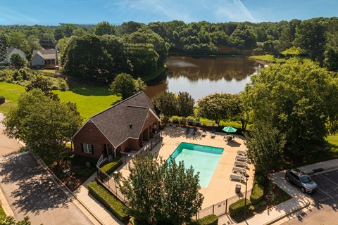 an aerial view of a house with a swimming pool and a lake in the background