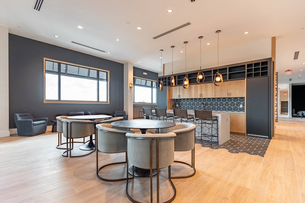 a communal area with tables and chairs and a kitchen with a fireplace