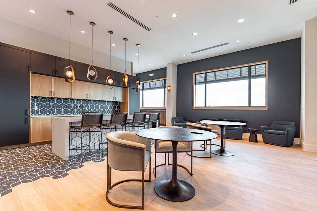 a lounge area with tables and chairs and a kitchen