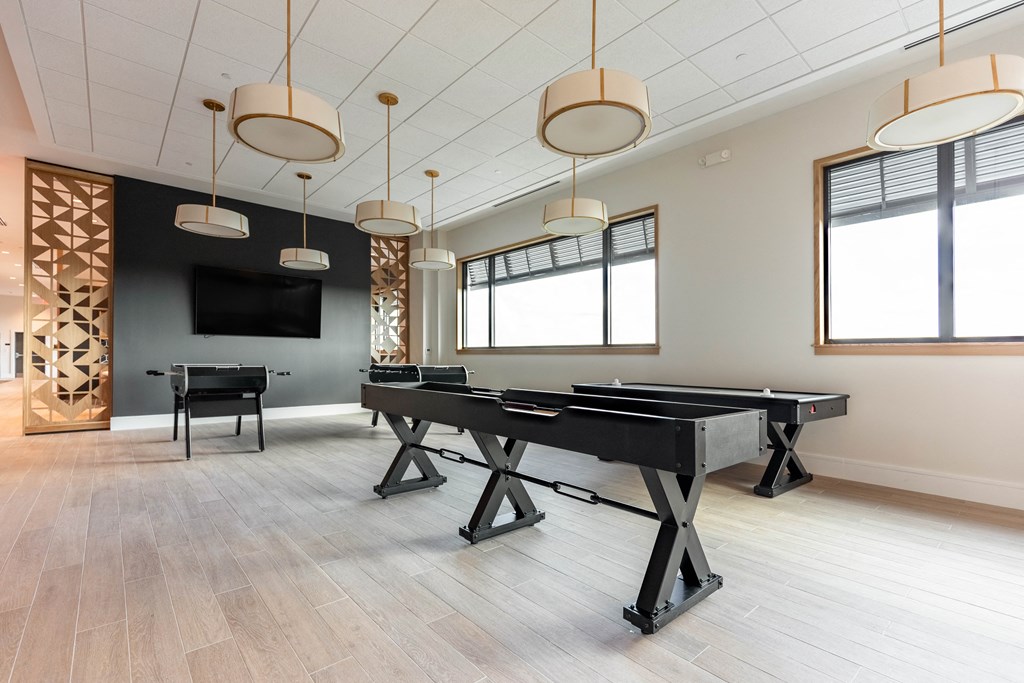 a rec room with a black piano and two chairs and a tv on the wall