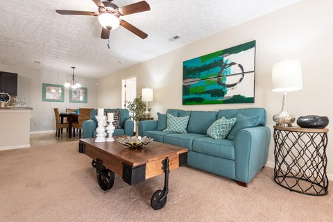 A living room with a blue couch and a painting on the wall.