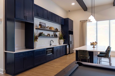 A modern kitchen with dark blue cabinets and a white countertop.