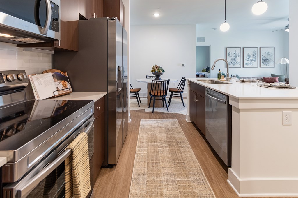 View down the kitchen with a refrigerator, oven, and sink.