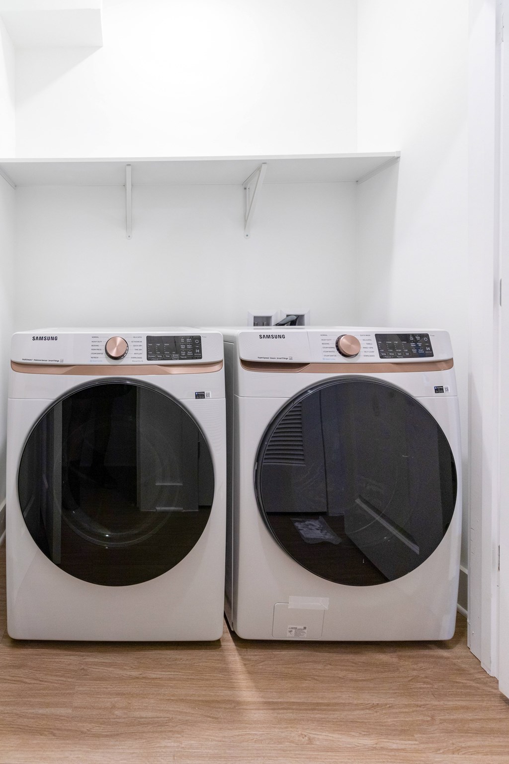 Two Samsung front loading washing machines in a laundry room.