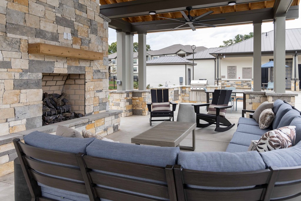 Outdoor patio with a stone fireplace with sectional for seating.