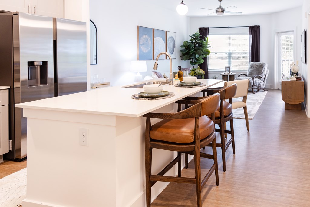 Interior Unit kitchen with a white island and wooden chairs.