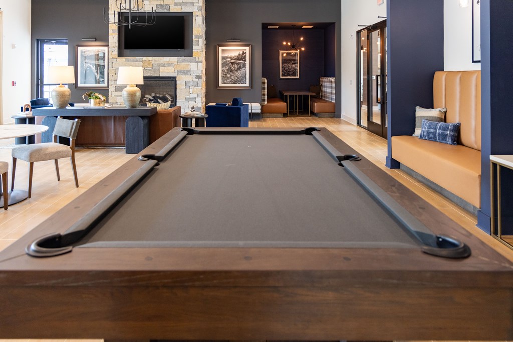Close up of a pool table in the middle of a room with a fireplace and a TV behind.