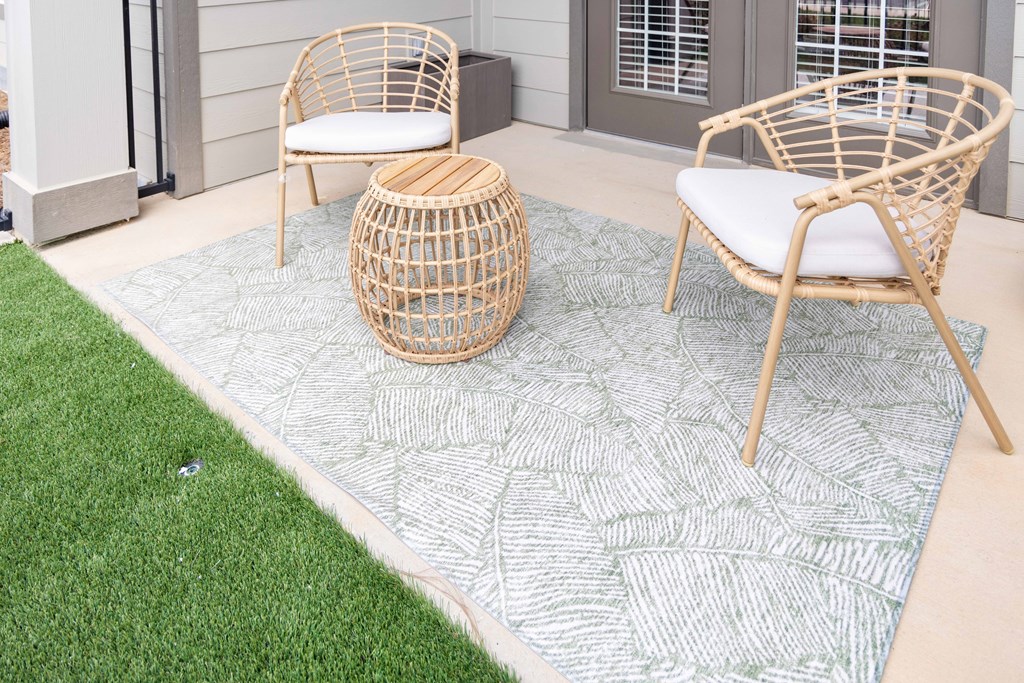 Outdoor patio with wicker chairs and ottoman.