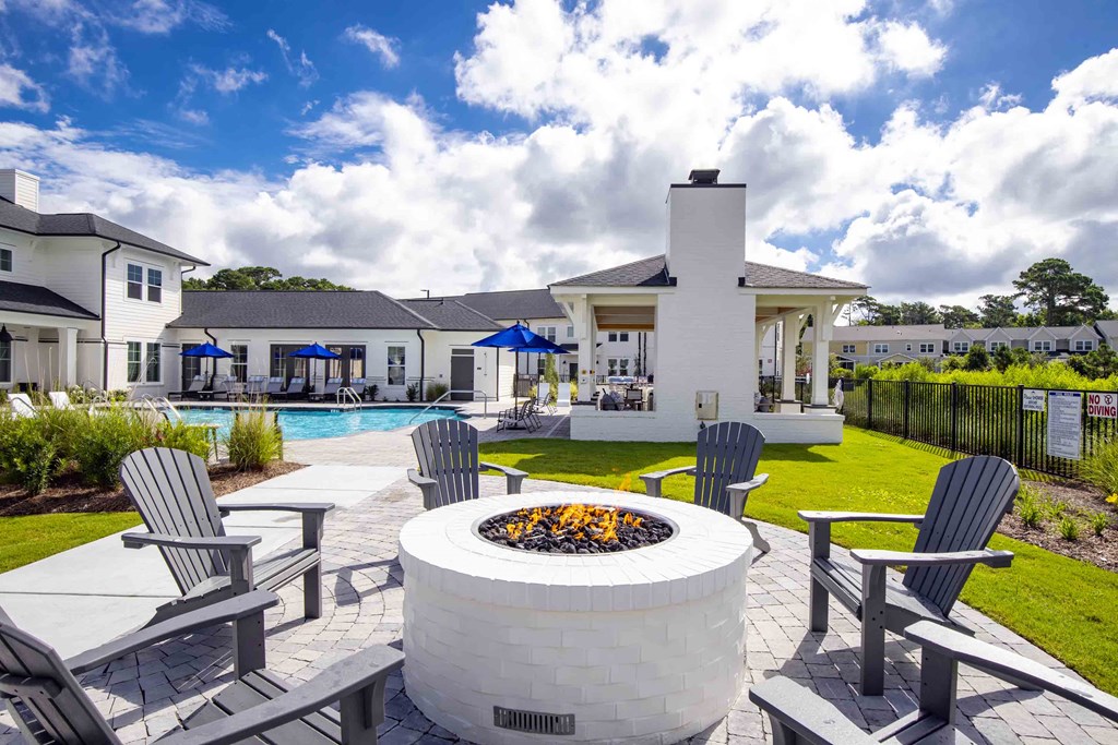 an outdoor patio with a fire pit and chairs and a pool