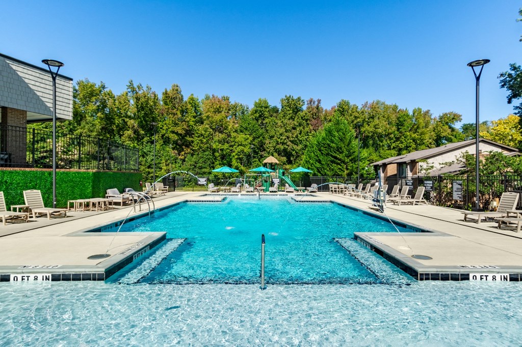 a swimming pool with chairs and umbrellas at the resort on a sunny day