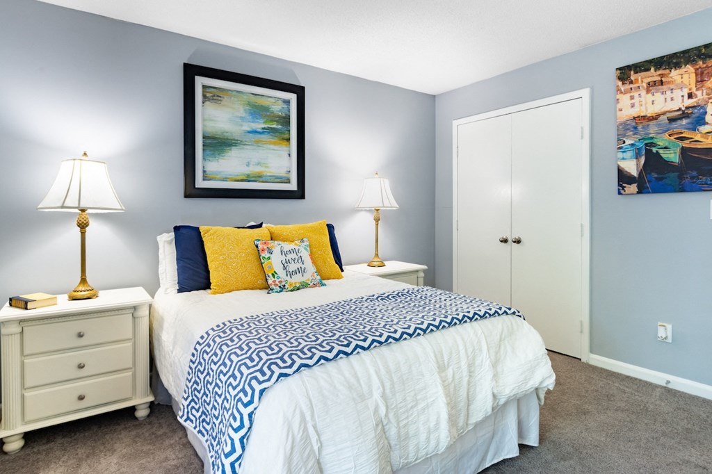 a blue and white bedroom with a bed and blue and yellow pillows