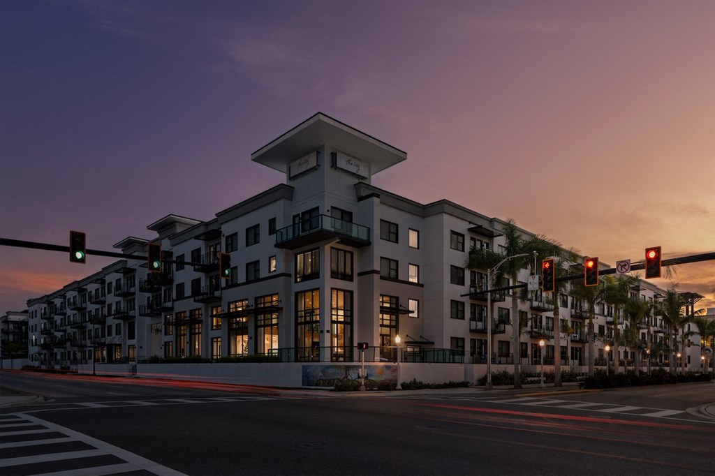 A modern building with a unique design is lit up at dusk.