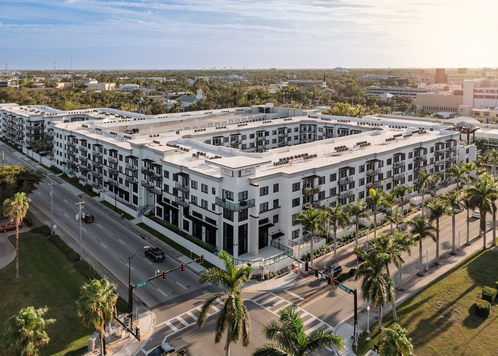 A large white building with a lot of windows and palm trees in front of it.