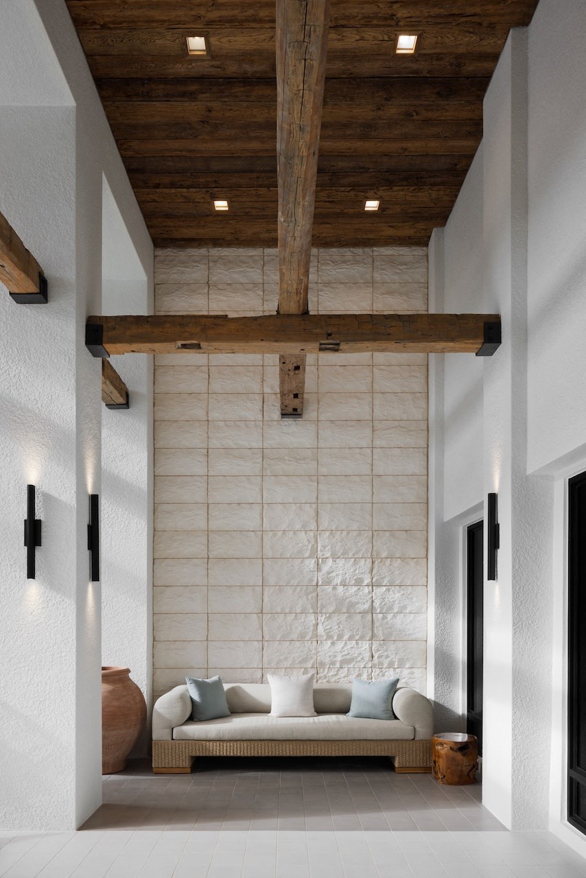 A white couch with pillows sits under a wooden beam in a room.