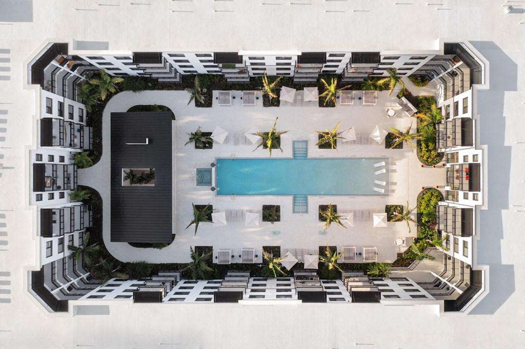 A modern building with a pool and palm trees.