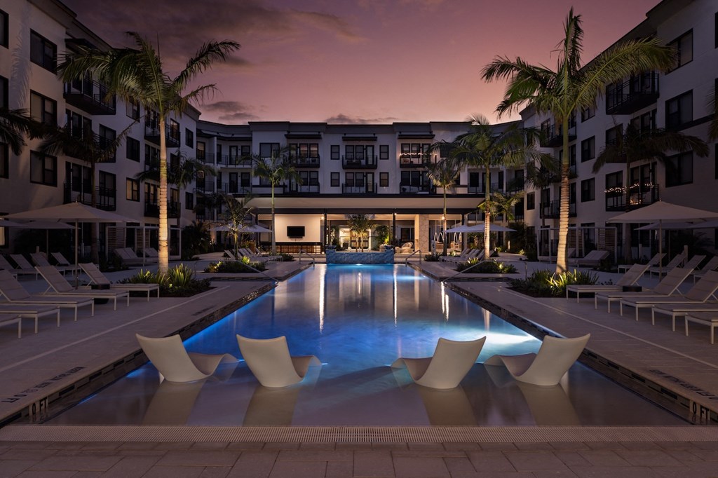 A large swimming pool surrounded by lounge chairs and palm trees.
