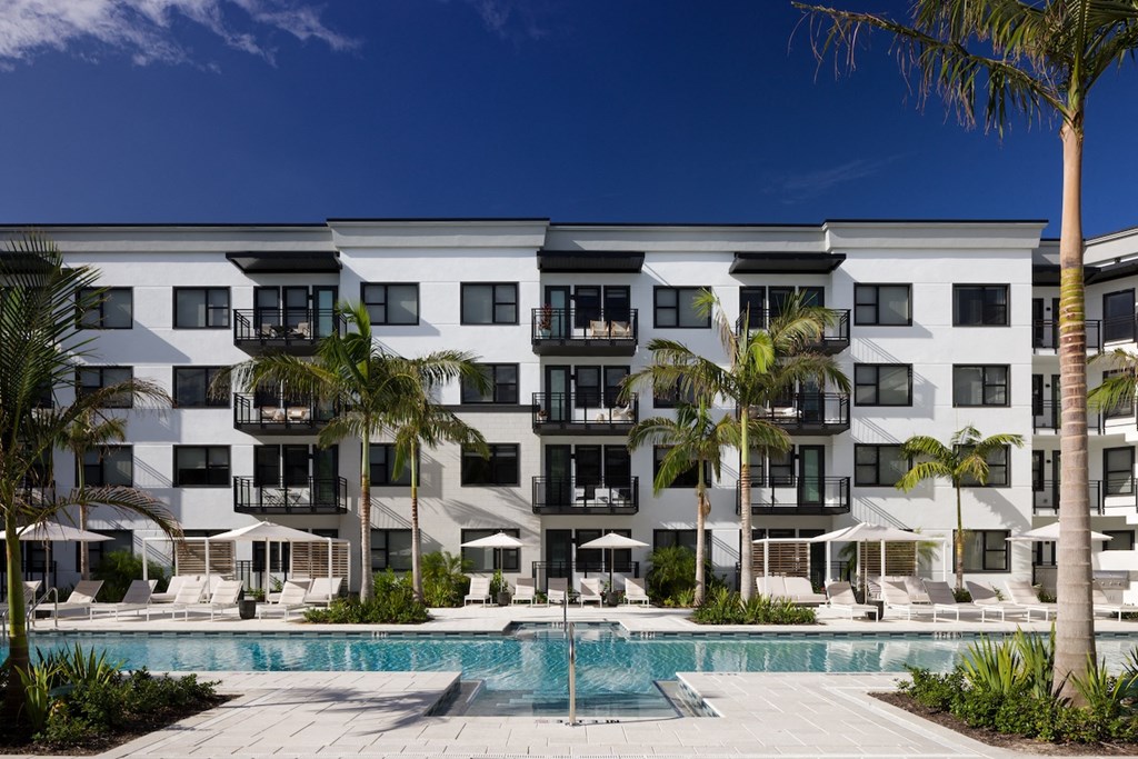A white building with a pool in front of it.