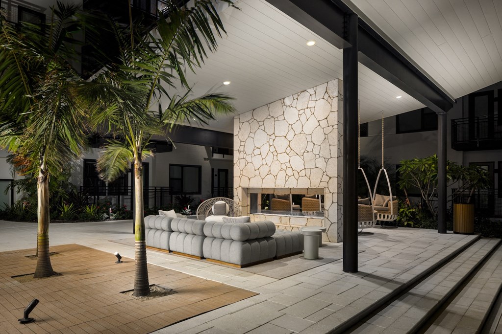 A modern outdoor living space with a white sofa and a wooden floor.