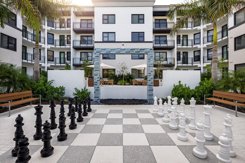 A giant chess board in the middle of a courtyard surrounded by buildings.