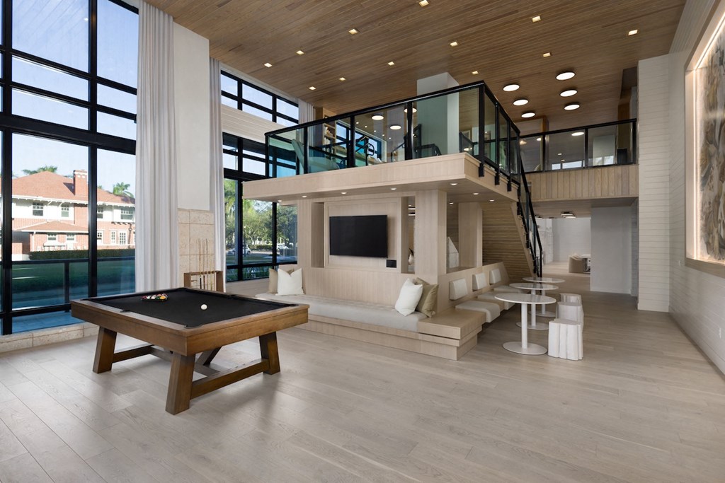 A billiard table is in the middle of a room with a balcony.