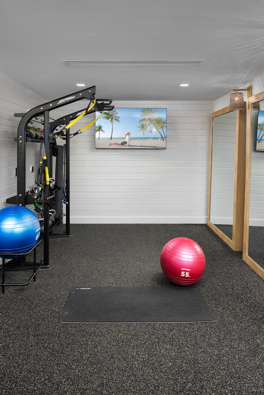 A gym room with a blue and red ball and a black mat.