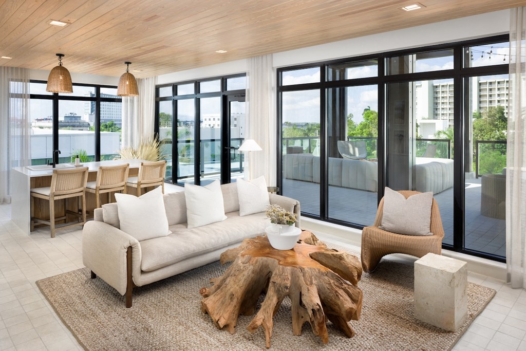 A modern living room with a large couch, a coffee table, and a view of the city.
