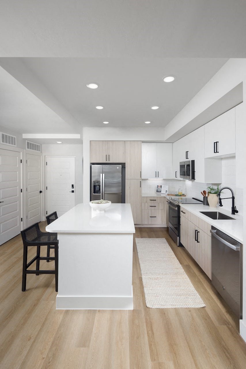 A modern kitchen with a white island and wooden floors.