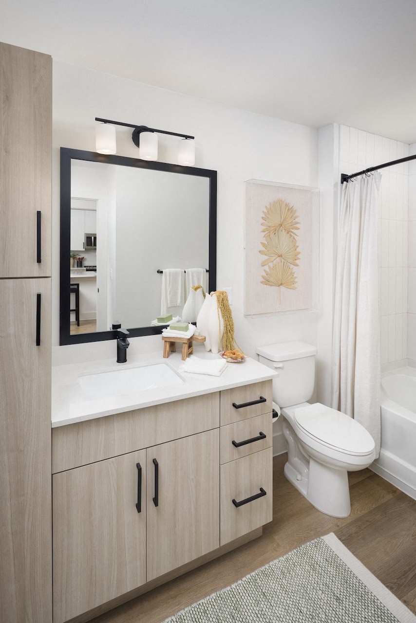 A bathroom with a white toilet, sink, and wooden cabinets.