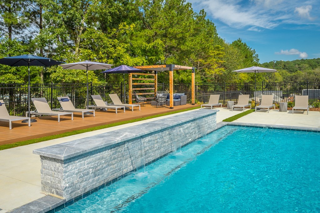 a swimming pool with chairs and umbrellas next to a resort style pool