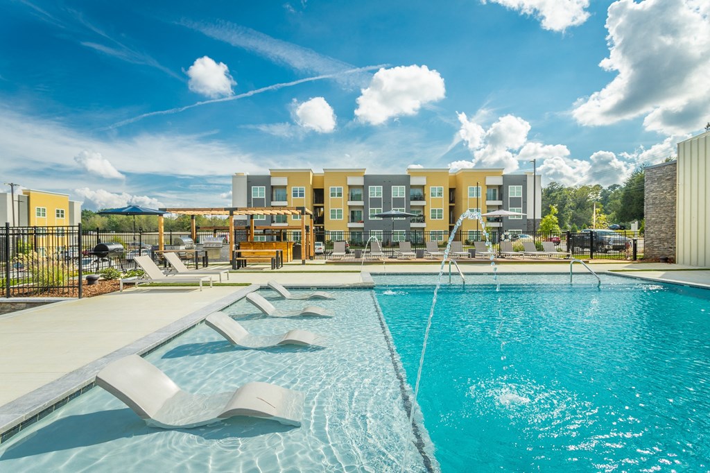 a swimming pool with two chairs and a building in the background
