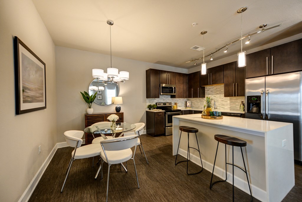a kitchen and dining area with a large island and a stainless steel refrigerator